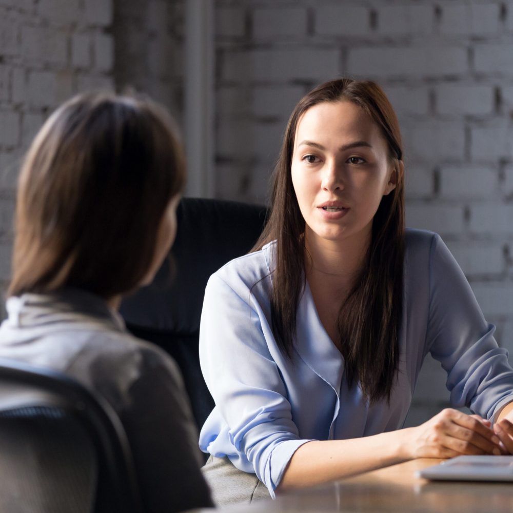 Serious professional female advisor consulting client at meeting talking having business conversation or making offer, insurer giving advice, mentor teaching intern, hr speaking at job interview