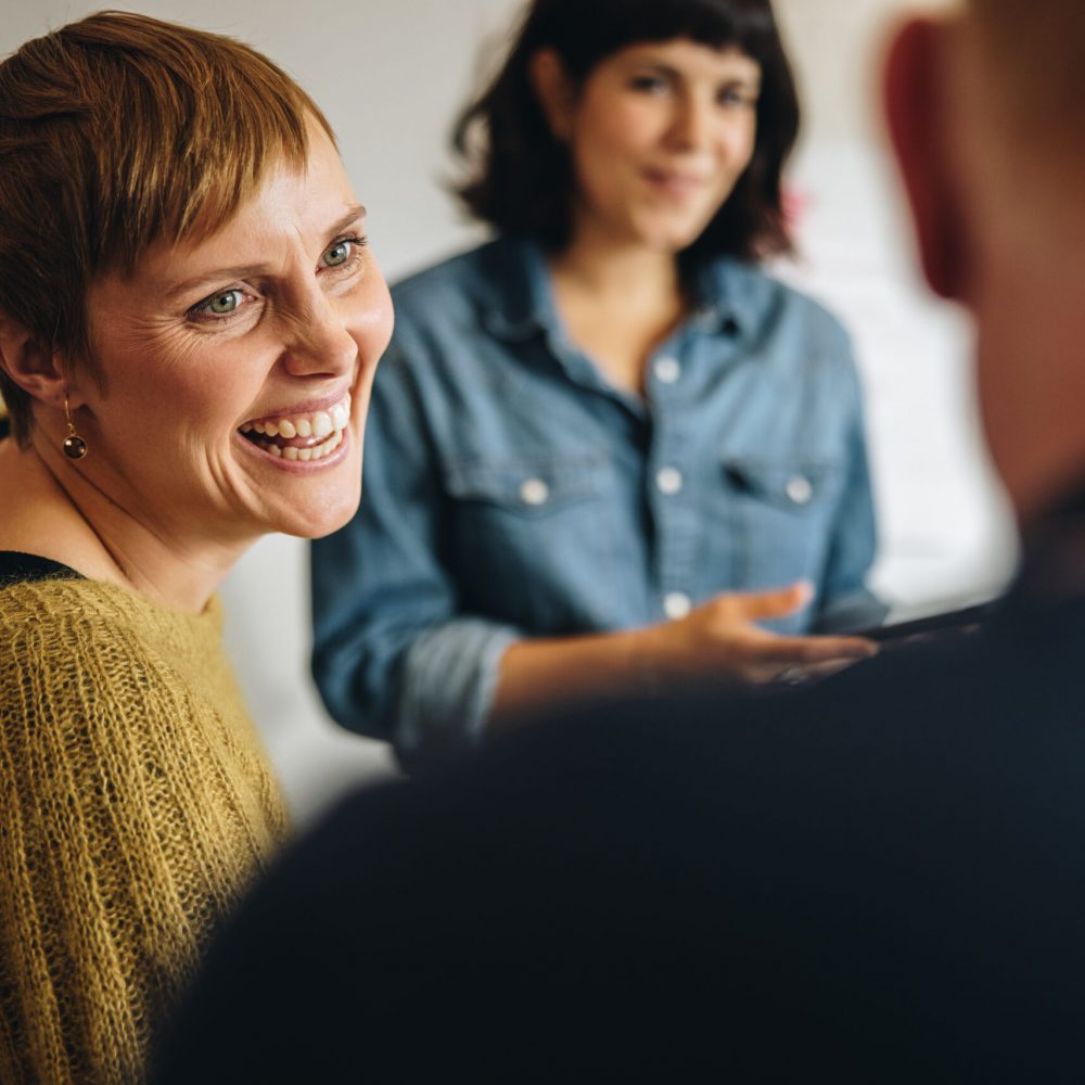 Businesswoman smiling during a meeting in office. Cheerful female professional looking at male colleague and smiling.
