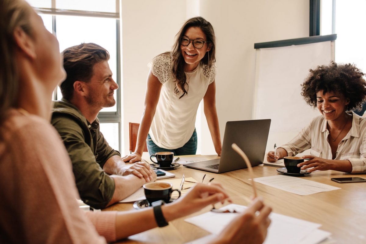 Group of multi ethnic executives discussing during a meeting. Business man and woman sitting around table at office and smiling.